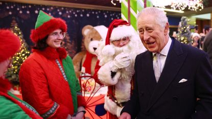 King Charles III reacts as he meets a Father Christmas during his visit to the Christmas Market at Ealing Broadway Shopping Centre in west London on December 7, 2023