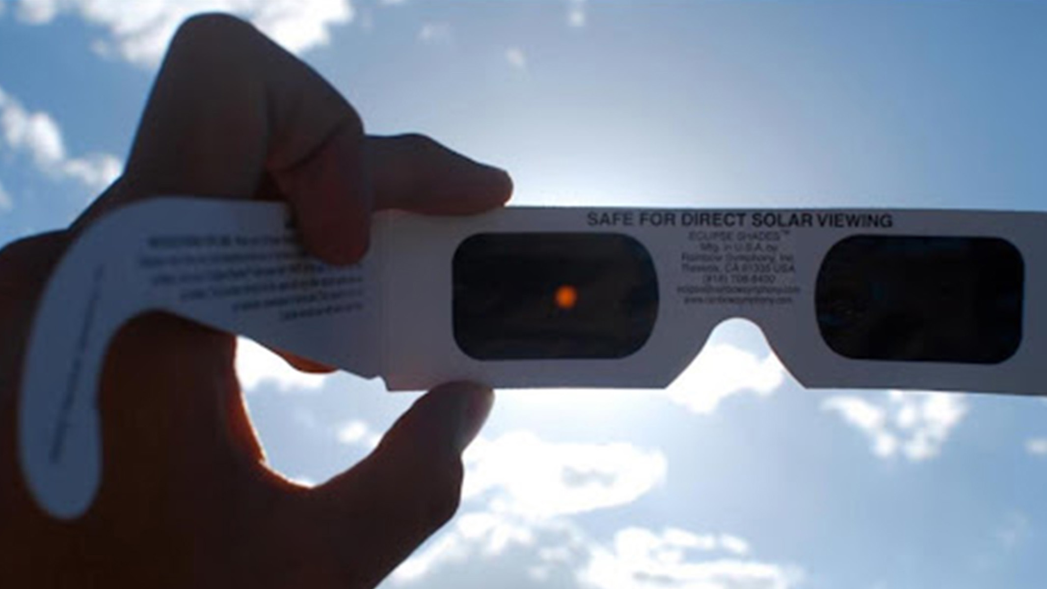 A pair of cardboard solar glasses being inspected