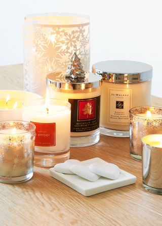 a collection of scented candles on a wooden sideboard