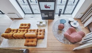 An aerial view of the showroom's ground floor. Visible are the Camaleonda modular sofa by Mario Bellini in caramel coloured leather and fabric, and a red and white striped UP chair by Gaetano Pesce