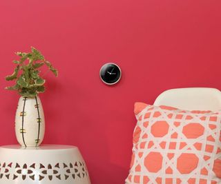 A smart thermostat on a pink wall