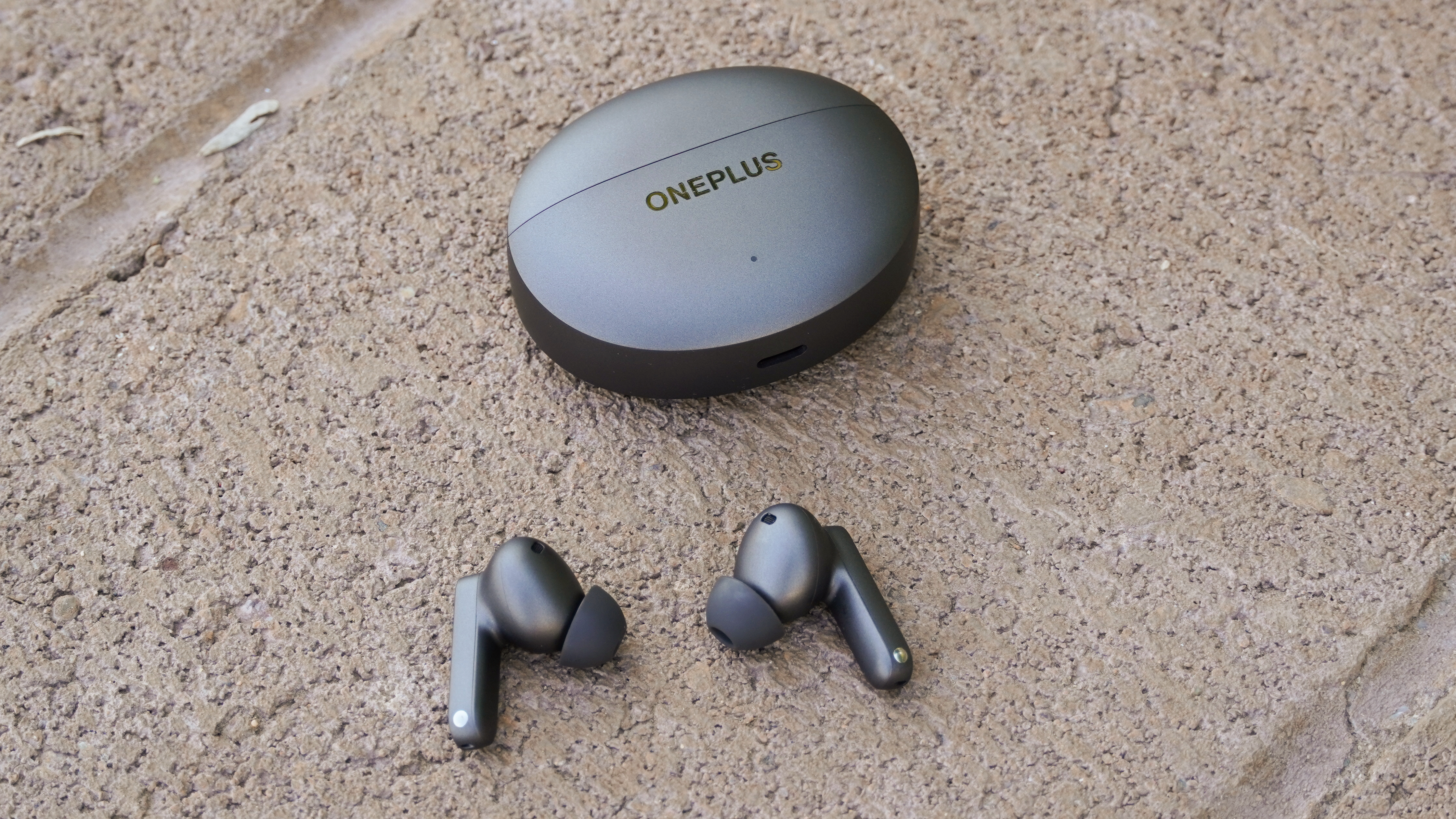 The OnePlus Buds 4 in Storm Gray beside their case.