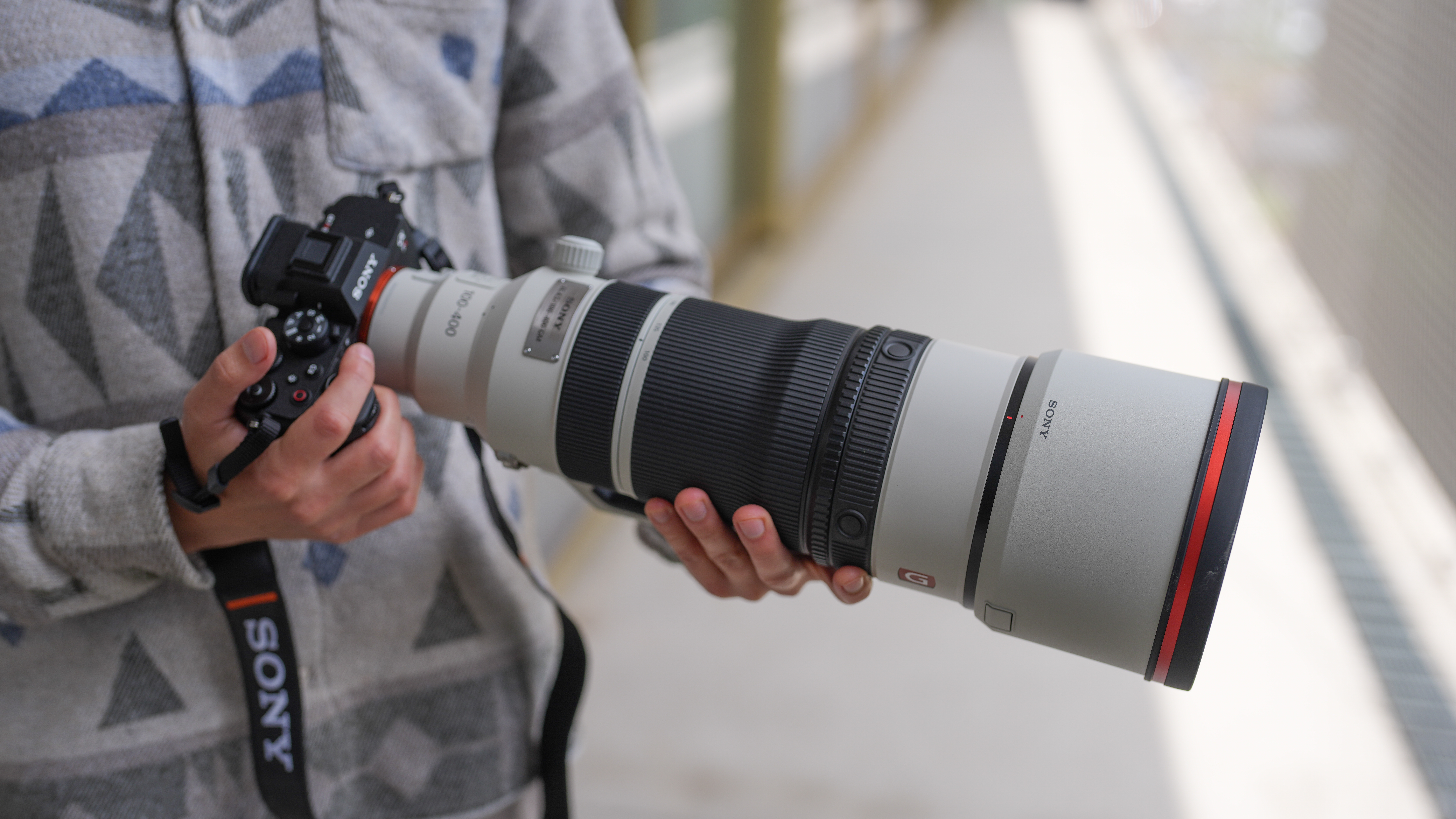 An image of a man holding the Sony A7R VI camera with the Sony 100-400mm f/4.5 GM lens attached.