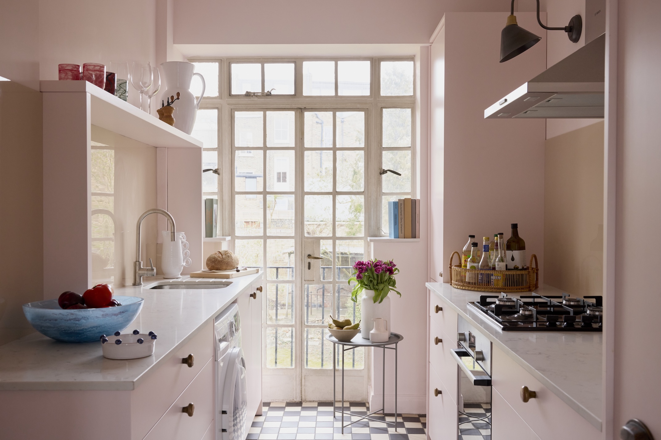 A small pale pink gelley kitchen with french doors at the end