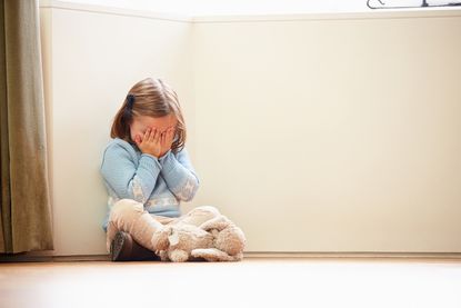 A little girl sits and cries.