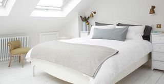 White attic bedroom with bed under windows to support the question can you sleep with a dehumidifier on