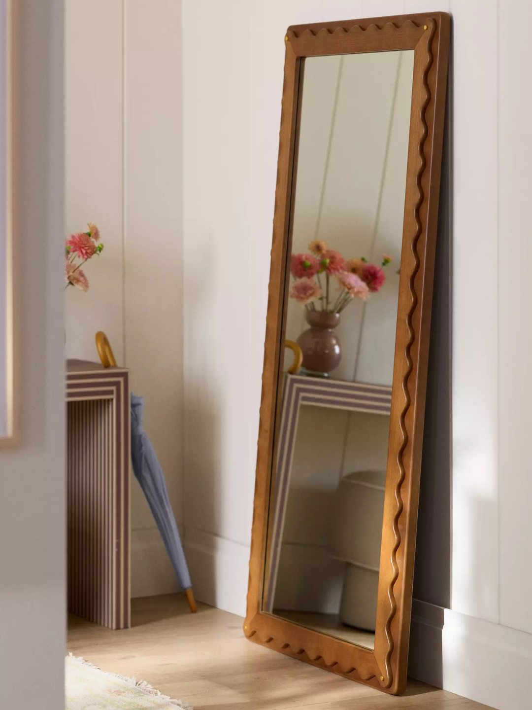 A living room with a wavy wood mirror on the floor