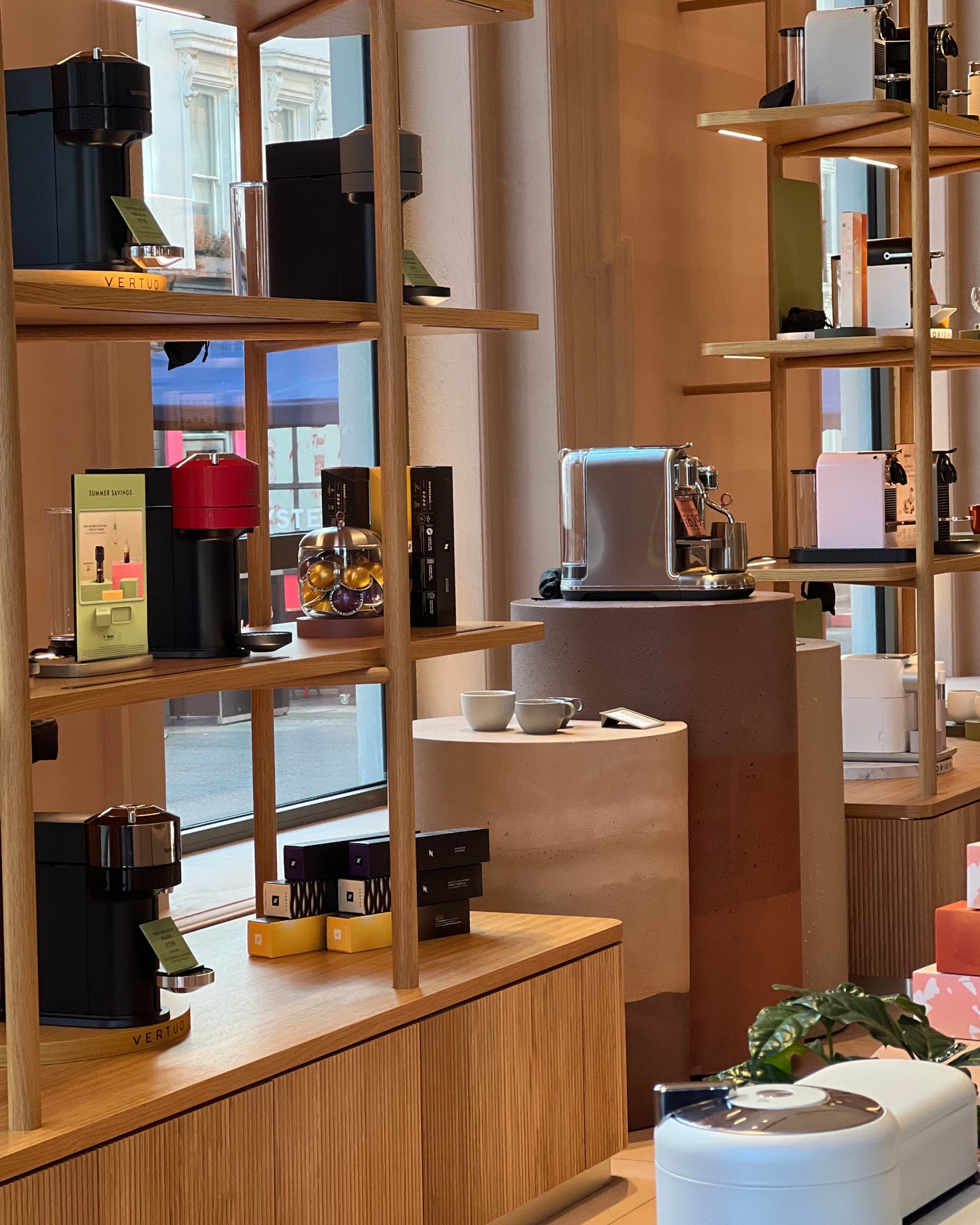 Image of several different Nespresso machines displayed across wooden shelving in a London Nespresso showroom.