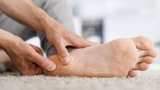 Person holding the heel of their bare foot