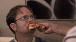 Dwight with a piece of pizza being fed to him in The Office