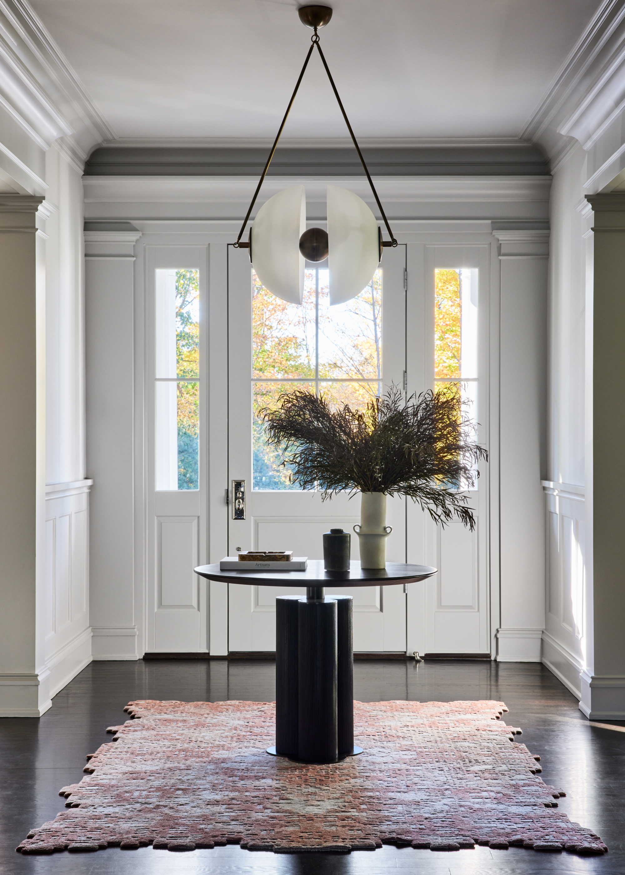 an entryway with a table and statement light