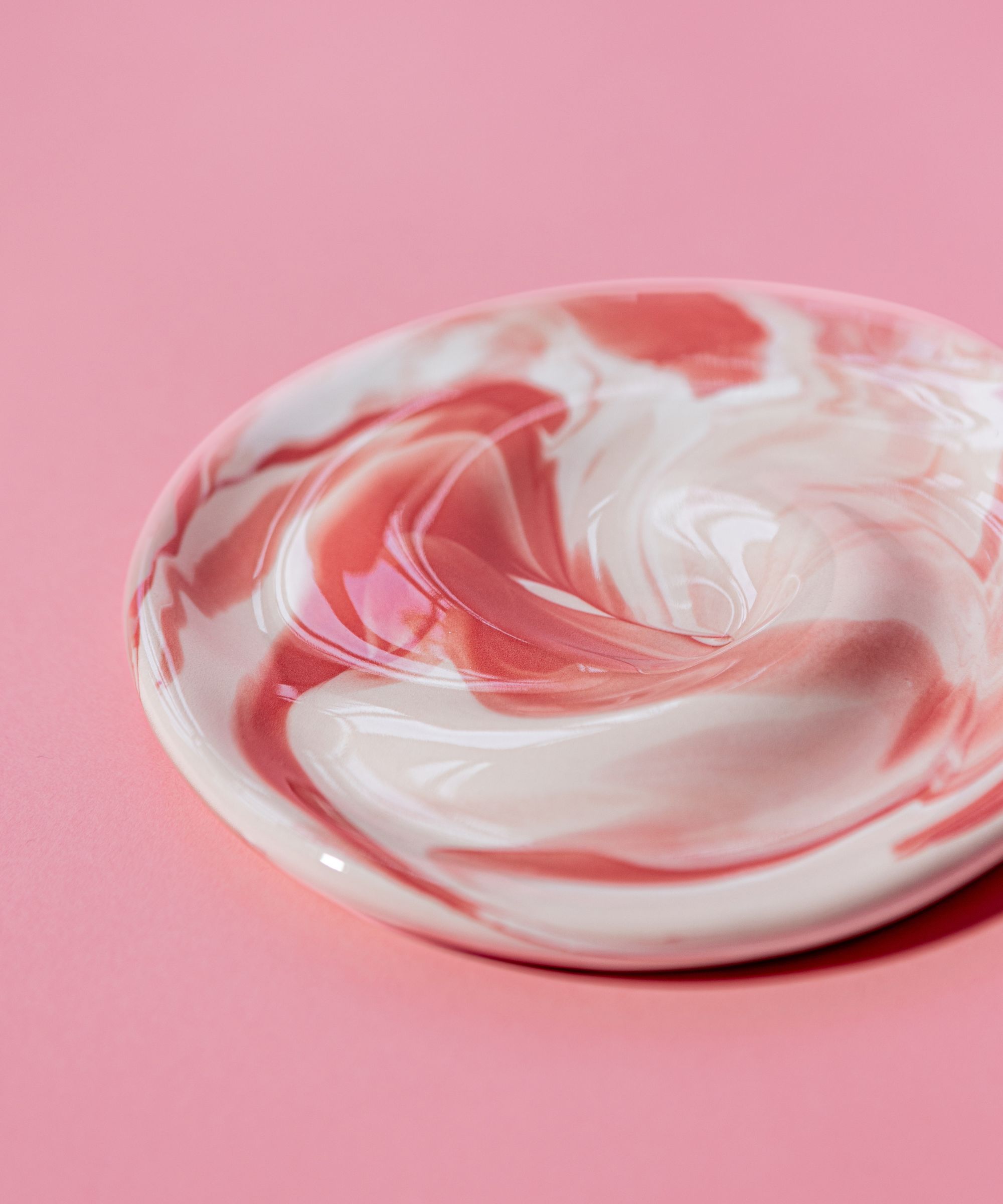 pink and white glossy plate with swirling shape on pink background
