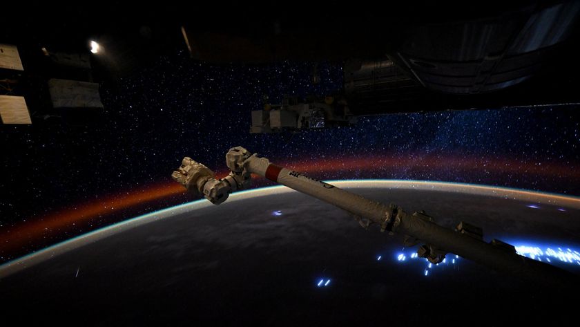 a streak of light crosses a starry sky above a dark earth below it