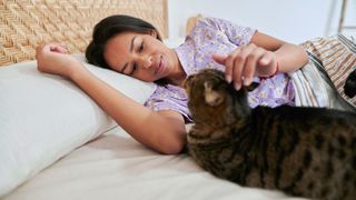 A person lying in bed with a cat next to them