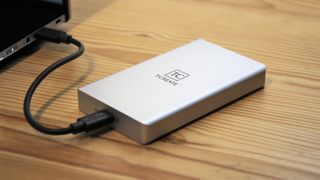 T-Create CLASSIC External SSD on a wooden desk and hooked up to a laptop
