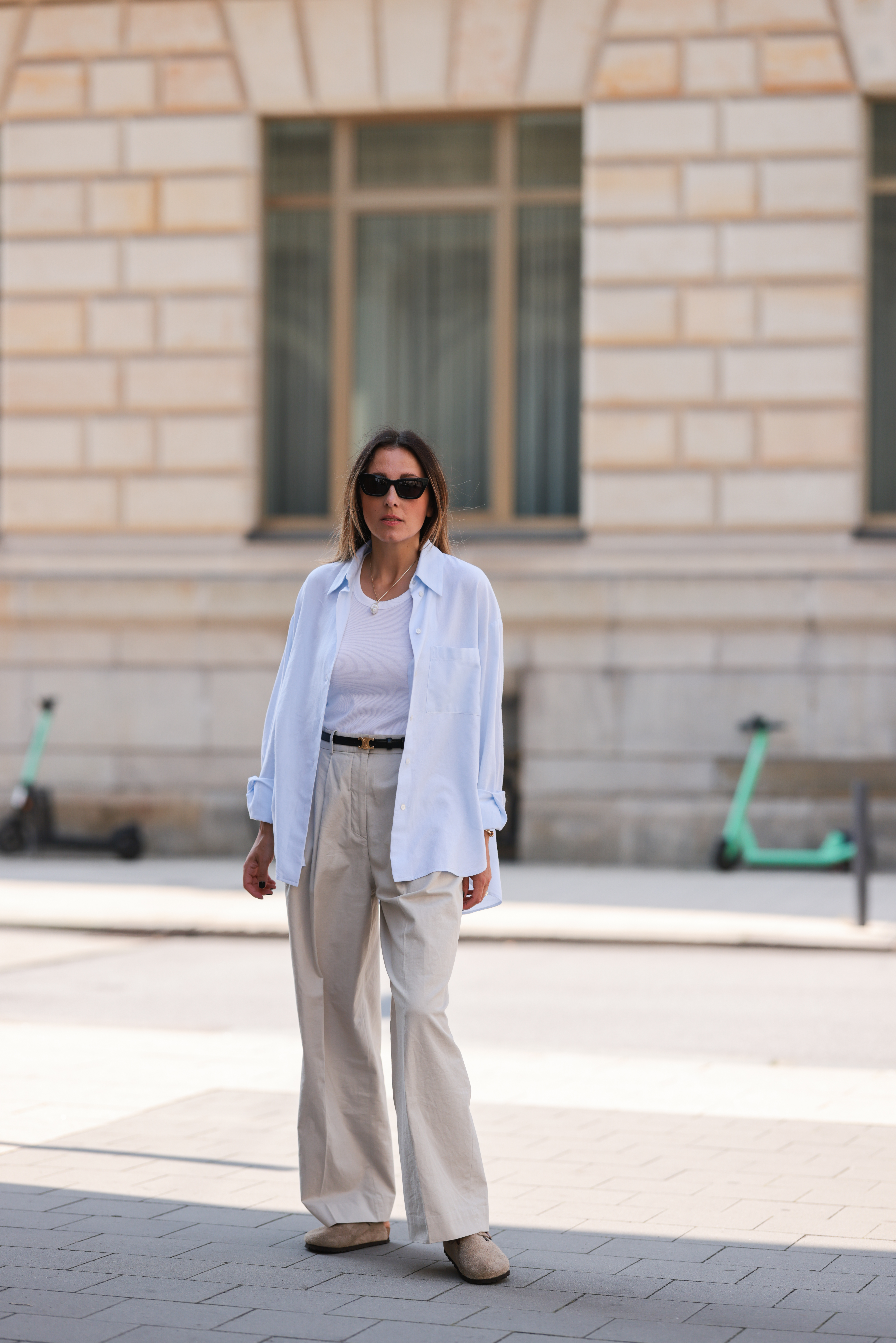 Woman wearing trousers, a shirt, vest, and Birkenstock clogs