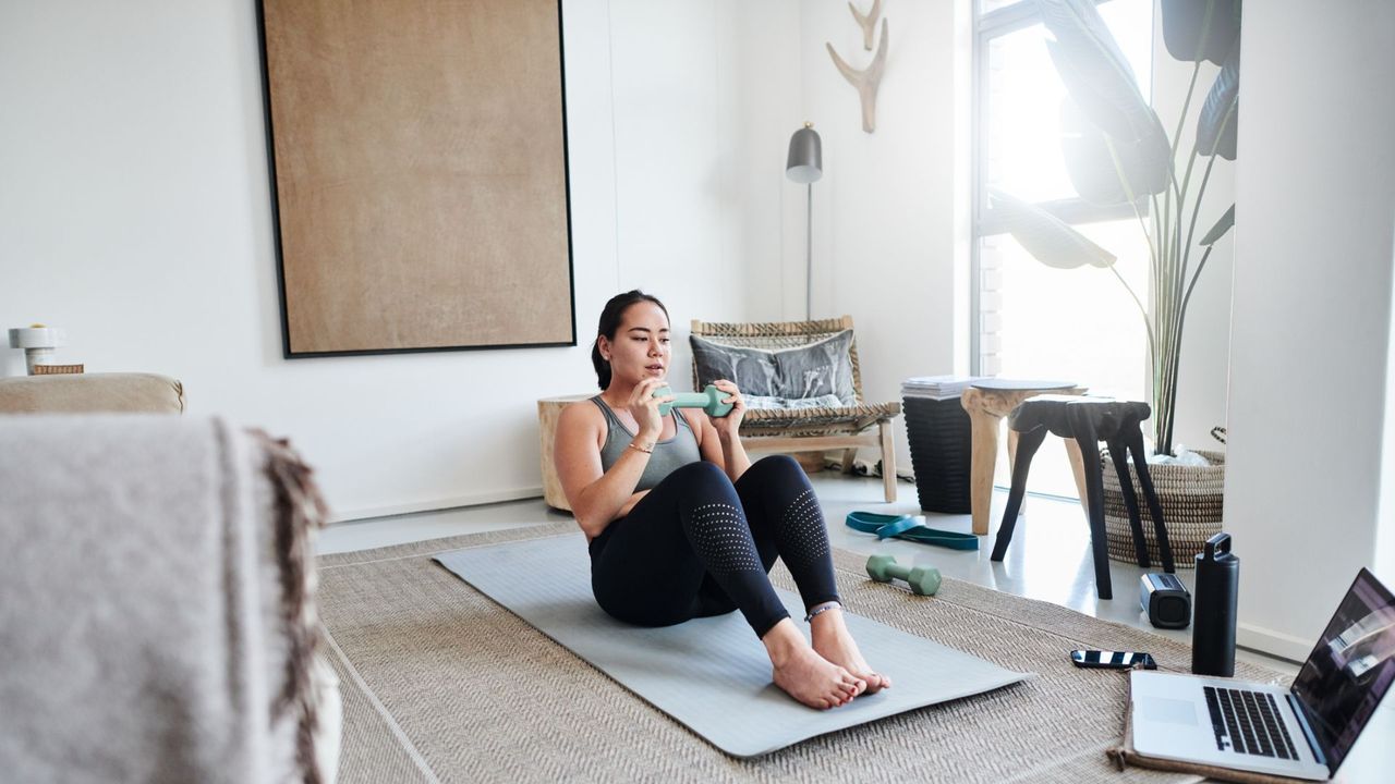 A woman performing abs exercises with a dumbbell