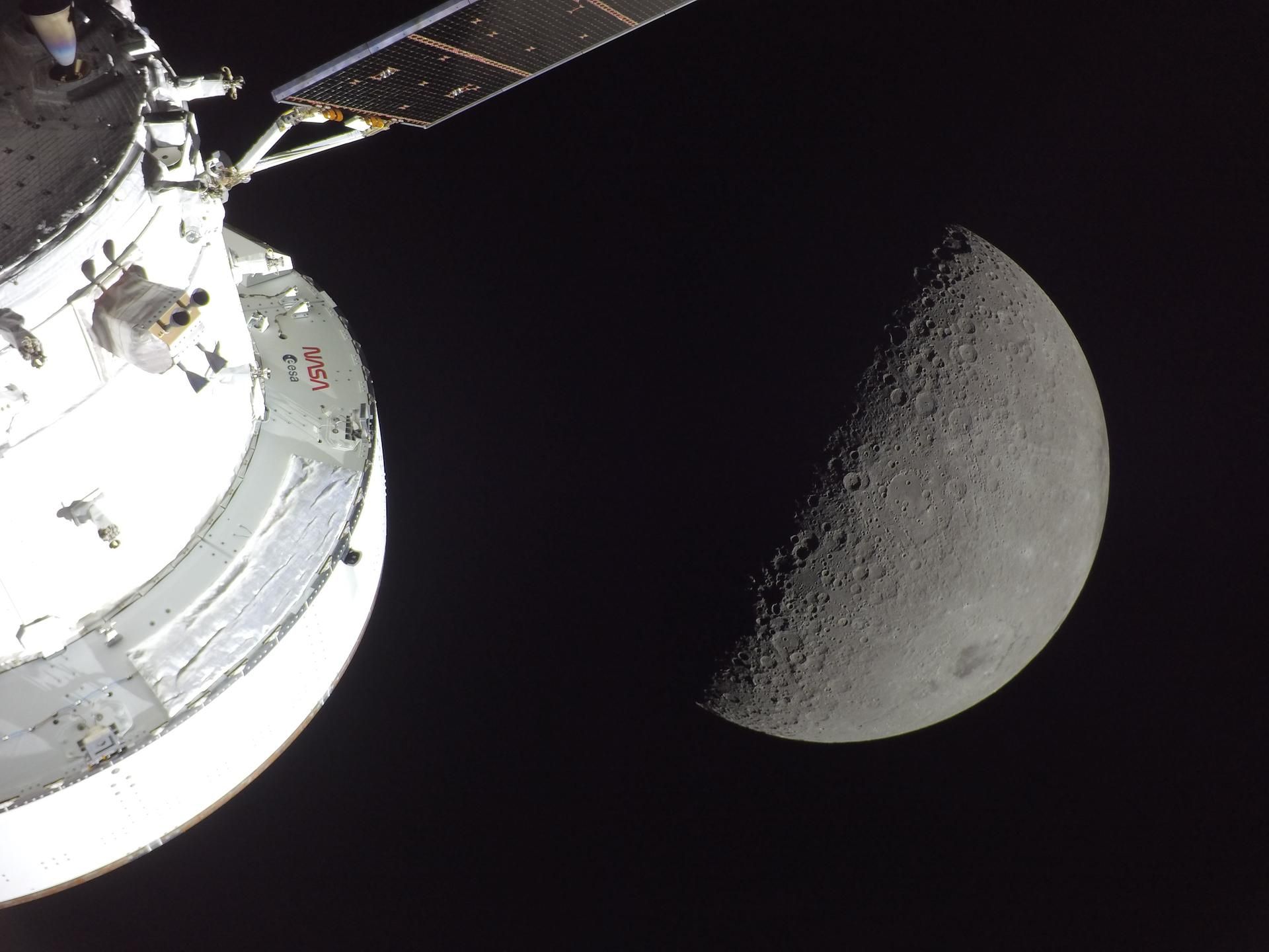 A gray moon with part of a spacecraft in the foreground
