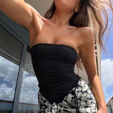 @emmaleger selfie wearing a black strapless swimsuit and printed pareo