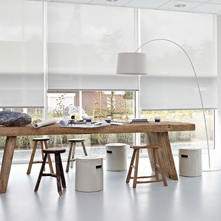 roller blinds with wooden table and stools and floor lamp