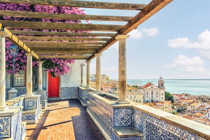 View of Lisbon and ocean from a veranda covered in azulejos, or blue tile common to Portugal.