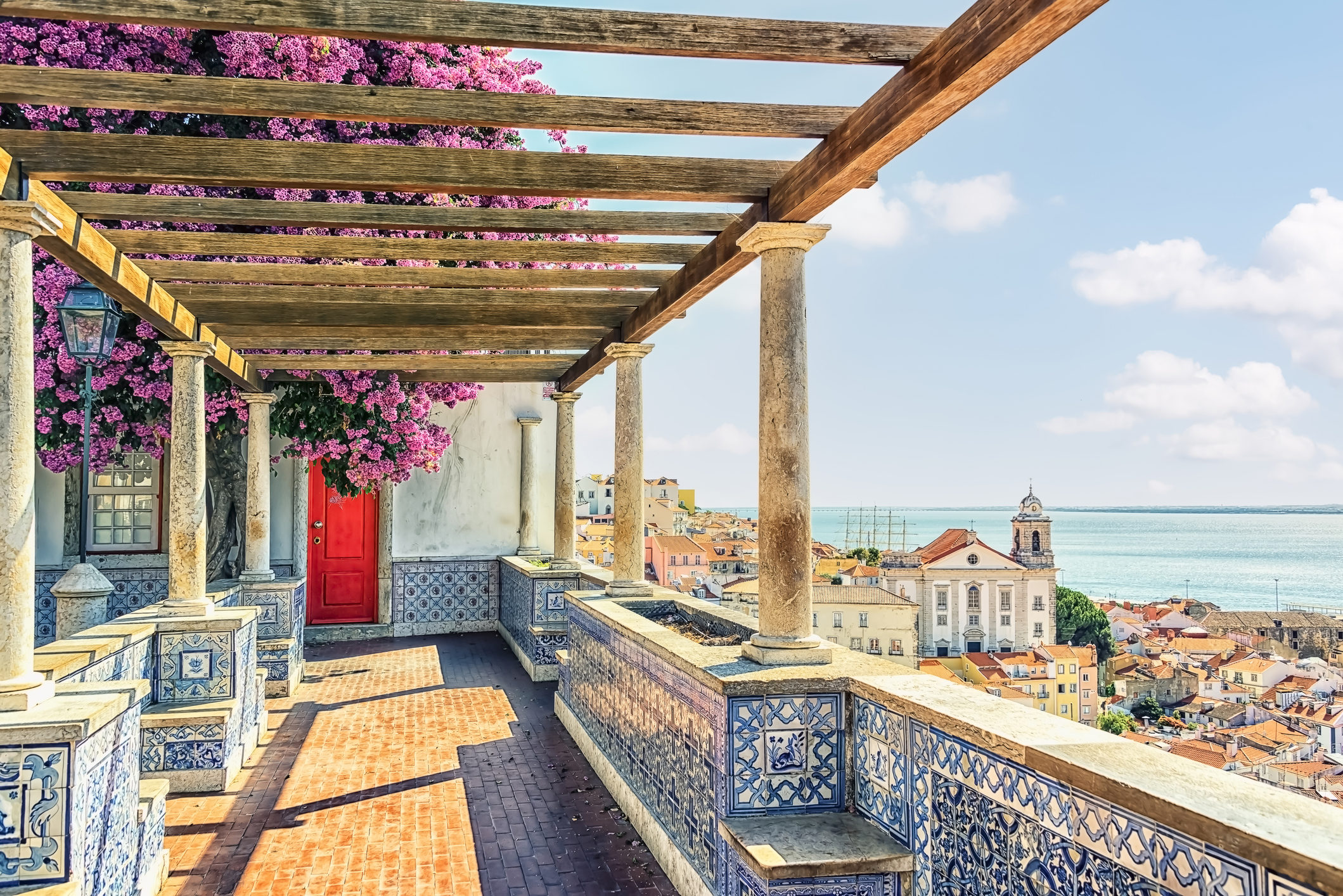 View of Lisbon and ocean from a veranda covered in azulejos, or blue tile common to Portugal.