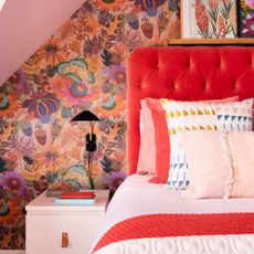 Bedroom with multicoloured walls, orange-red headboard, pink table and pink ceiling