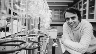 A black and white photo of Carl Sagan in a laboratory