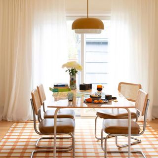 A large plaid orange and cream wool rug sitting on top of a mid-century style dining room table