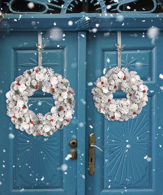 Two frosted white wreaths hanging on a blue front door