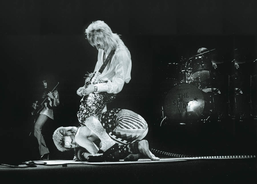 Mick Ronson stands astride David Bowie as they perform on stage on the Ziggy Stardust tour, Earls Court Arena, London, 12th May 1973