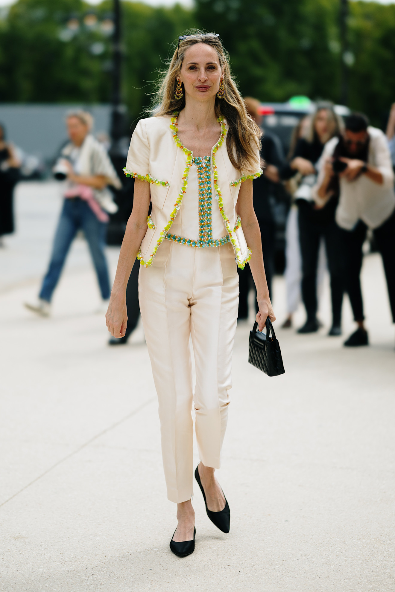 Lauren Santo Domingo wearing cream pants, a green embroidered top and jacket and black pointed toe flats