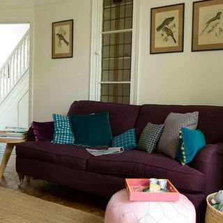 living room with white wall violet sofa with designed cushion frames on wall