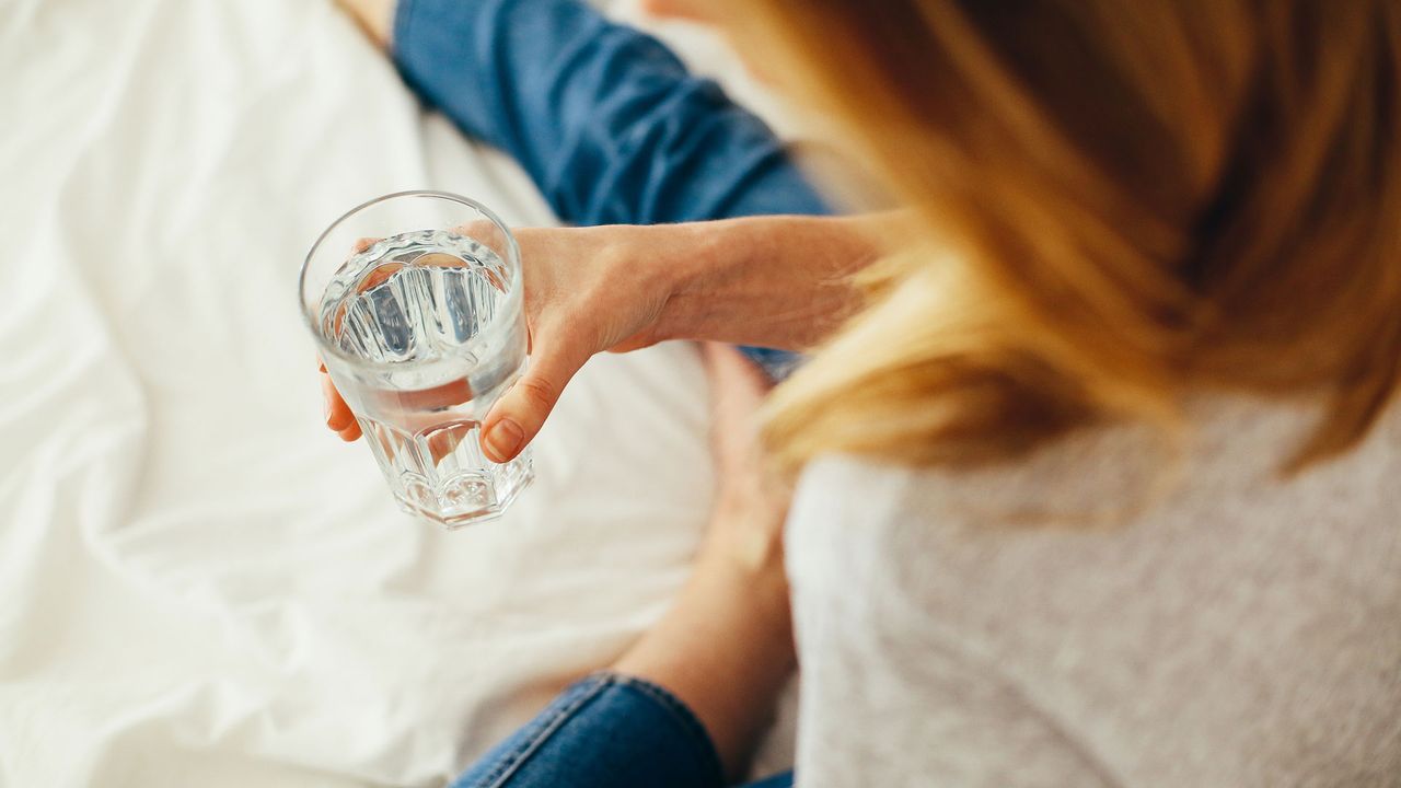 A hand holding a glass of water