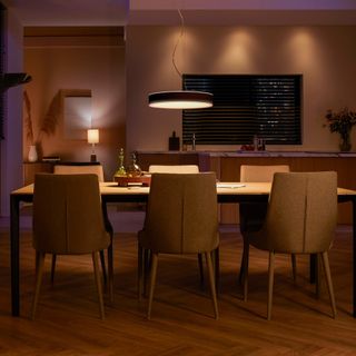 a dining table and six chairs in an open plan space with a low hung pendant