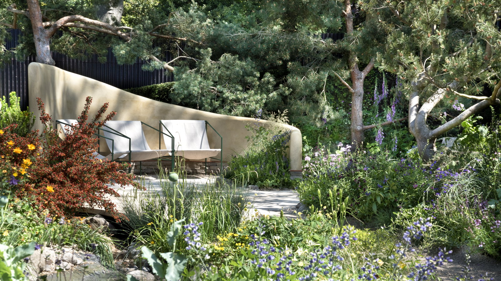 A show garden with seating, trees, and shrubs at the Chelsea Flower Show 