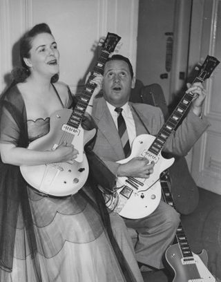 Les Paul (1915 - 2009) and his wife Mary Ford (1924 - 1977) demonstrate two of Paul's new electric guitars during a press reception at the Savoy Hotel in London, 9th September 1952.