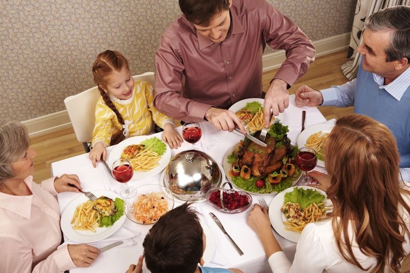 A family sits around a Thanksgiving turkey and feast.