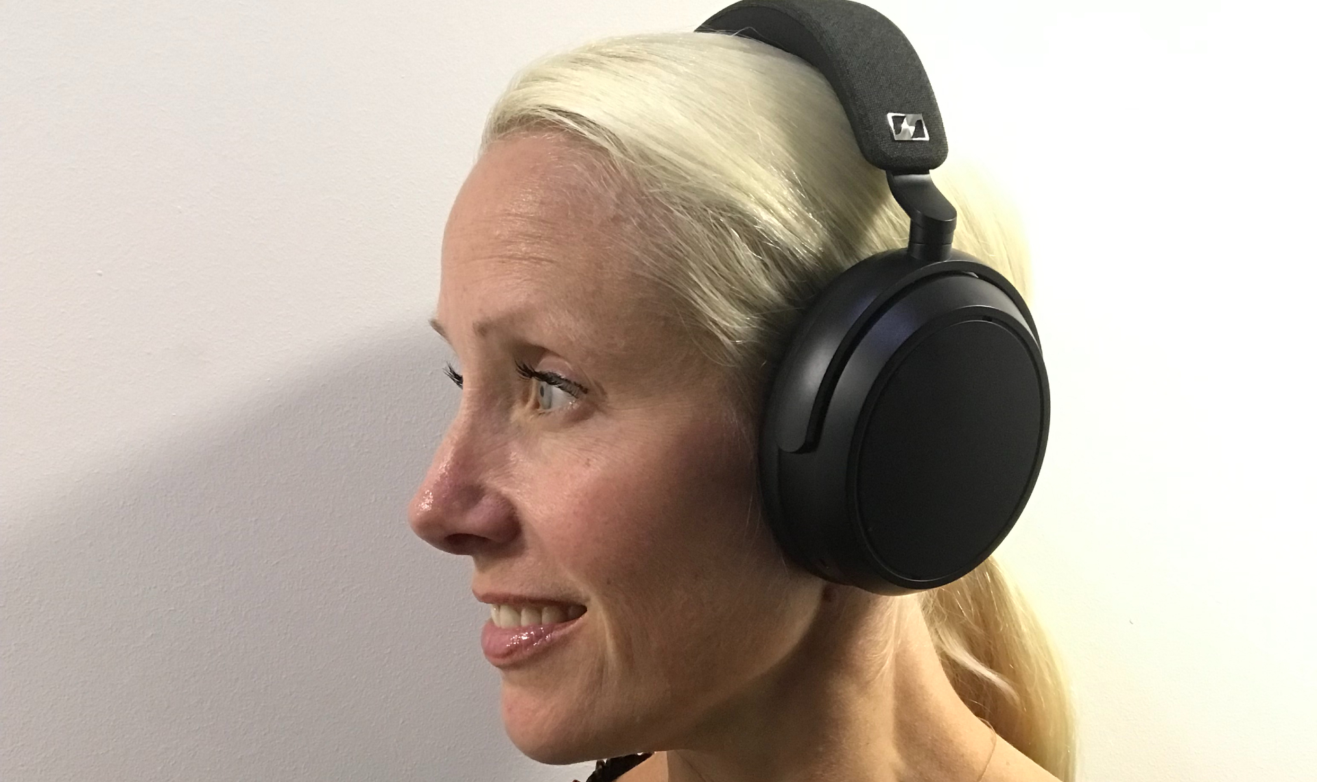 Senior Editor Becky Scarrott wears Sennheiser Momentum 4 wireless headphones on a white background