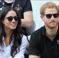 Prince Harry and Meghan Markle wearing sunglasses sitting at the 2017 Invictus Games