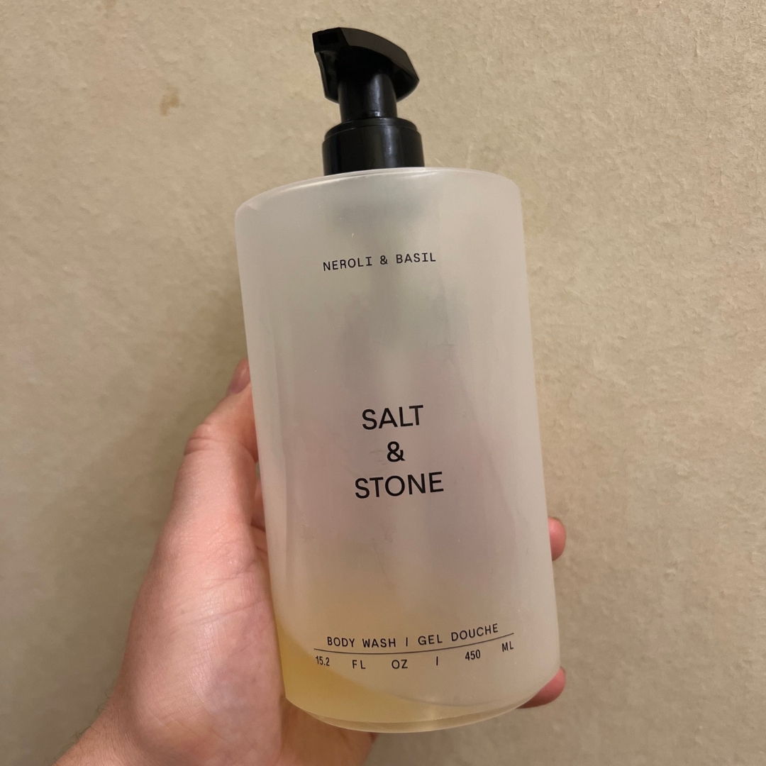 Hand holding empty bottle of Salt &amp;amp; Stone Neroli and Basil Body Wash