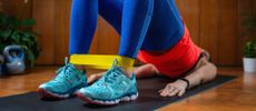 Woman exercising at home on mat with resistance band around ankles