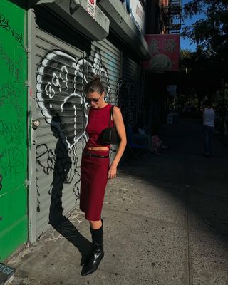 Woman wearing matching red set with tall black boots.