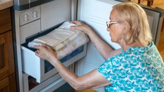 Woman putting bedclothes in the freezer drawer
