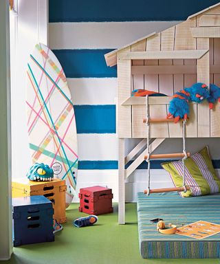 kids bedroom with timber treehouse and striped wall with green rubber floor
