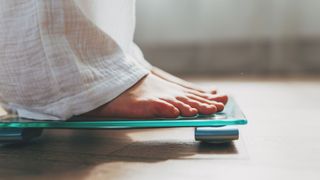Woman's feet standing on weighing scales