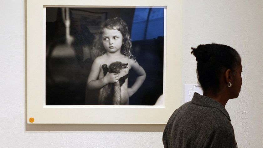 A person walks by the Sally Mann photograph &quot;Holding the Weasel&quot; at an art gallery