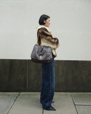 woman wearing cropped fur jacket and baggy jeans with stiletto heels