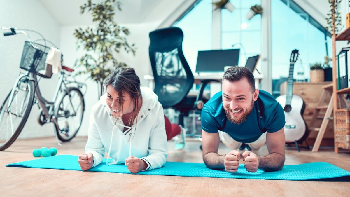 Man and woman perform forearm plank abs exercise at home