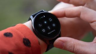OnePlus Watch runt en handled. Visar kontrollpanelen.